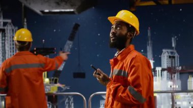 Endüstriyel mühendis, petrol çıkarma faaliyetlerini denizaşırı platformlarda koordine etmek için telsiz kullanıyor, doğal gaz ve yakıt kontrol operasyonlarını desteklemek için radyo cihazına konuşuyor. Kamera B.