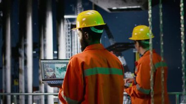 Afrika kökenli Amerikalı işçiler gece kıyı sondaj kulesinde doğal gaz ve petrol çıkarma kurallarına uyulmasını sağlamak için inceleme ve emisyon takibi yapıyorlar. Kamera B.