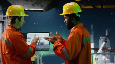 Çevre memurları aurora borealis altındaki kıyı petrol platformunu inceleyerek benzin çıkarma mühendisliğini izlemek için dizüstü bilgisayar kullanıyor. Okyanustan petrol üretim stratejisi. Kamera B.