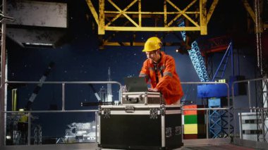 İşçi uzmanı, dizüstü bilgisayar yazılımı, terleme ve güvenli petrol sondajı üretimi için çabalarken, petrol çıkarma işlemini takip eden açık deniz petrol platformu konusunda endişeli. Kamera A.