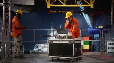 Sondaj kulesindeki erkek işçi telsizle denizaşırı platformlarda iletişim kurarak petrol ve gaz çıkarma sektöründeki meslektaşlarını koordine ediyor. Deniz kirliliği. Kamera A.