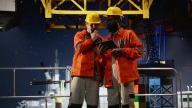 Deniz aşırı petrol sondaj kulesi mühendisleri sondaj operasyonlarını izlemek için telsiz kullanırlar. Sert şapkalar ve turuncu ceketlerle güvenliği sağlarlar. Verimli doğalgaz ve fosil yakıt çıkarma. Kamera A.