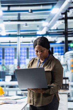 Siyahi yönetici, güneş paneli kalitesini bir fabrikada değerlendiriyor, veri raporlarını ve güneş panelleri için pürüzsüz üretim hattını sağlamak için içgörüyü analiz ediyor. Yeşil enerji üretimi.