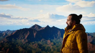 Yürüyüşçü dağın tepesine ulaşır ve başarılı bir tırmanıştan sonra zafer pozu verir. Bu da maceraya olan güveni yansıtır. Gezgin korkuları yenmenin kişisel başarısının tadını çıkarıyor. Kamera A.