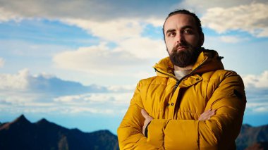 Yürüyüşçü zaferle bir dağın zirvesinde duruyor. Kolları zaferle yükseliyor. Kişisel başarısını başarılı bir tırmanışla kutluyor. Manzaralı manzara ve özgürlük için sonsuz gökyüzü. Kamera A.