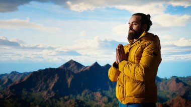 Keyifli bir doğa aşığı dağ sırasının tepesinde meditasyon yapıyor, meditasyon yapıyor ve rahatlık ve zihinsel berraklık için derin nefesler alıyor. Huzurlu zen yürüyüşçüsü tırmanmayı sever. Kamera A.