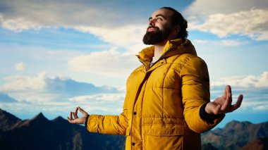 Dağın tepesinde meditasyon yapan maceraperest, tepeye başarıyla tırmanıyor ve manzaranın tadını çıkarıyor. Genç sakin zen yolcusu yürüyüş yapıyor ve meditasyon yapıyor. Kamera A.