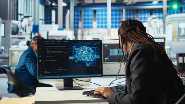 Fotovoltaik fabrikası programcısı yapay zeka kullanarak verileri analiz ediyor, sistem ölçümlerini gözden geçiriyor. Güneş panelleri, yapay zeka teknolojisi ve kamera A kullanılarak teknik sorun giderme teknisyenleri