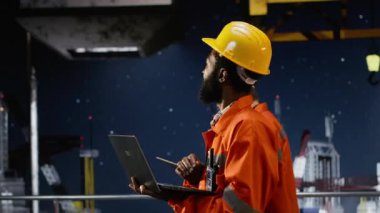 Petrol platformunun dijital incelemesini yapan siyah mühendis, endüstriyel faaliyetleri doğal gaz ve petrolü çıkarma yoluyla elde etmek için modern araçlarla izliyor. Sondaj kulesi. Kamera B.