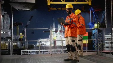 Kara kıyı mühendisi dizüstü bilgisayar kullanarak petrol sondaj platformunu izliyor ve doğal gaz ve petrol çıkarmasını kolaylaştırmak için verimli endüstriyel faaliyetler sağlıyor. Fosil yakıt pompalıyor. Kamera A.