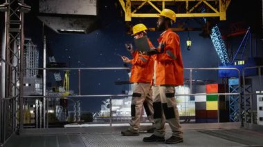 Deniz aşırı platformda çalışan siyah erkek mühendis, petrol ve fosil yakıtları elde etmek için endüstriyel deniz teknolojisini entegre ederek dizüstü bilgisayarla sondaj yönetimi yapıyor. Petrol endüstrisi. Kamera A.