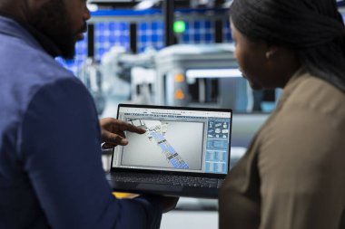 Günümüz yüksek teknolojili ve sürdürülebilir bir tesiste güneş enerjisi performansını denetleyen Afrikalı Amerikan mühendislik ekibi. Uzmanlar dizüstü bilgisayarda kalite kontrol yapıyorlar. Kapat..