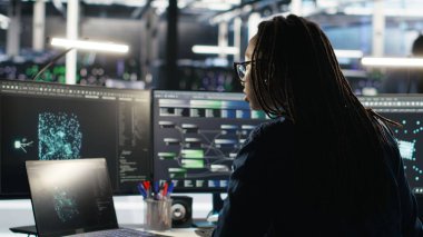 Sunucu tarım yazılım geliştiricisi yapay zeka oluşturulmuş veri analizi grafiklerini yorumluyor. Yapay zeka programı kullanan veri merkezi uzmanı öngörü sistemi ölçümlerini gösteriyor, kamera B