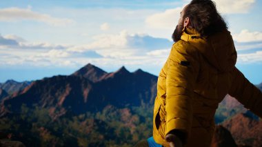 Macera Avcısı, başarılı bir tırmanışın hazzıyla zirvede durur. Gurur duyar ve dağın tepesindeki sert rüzgarın tadını çıkarır. Özgürlüğü ve doğayı sevmek. Kamera A.