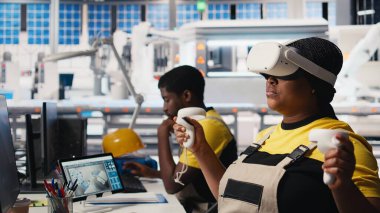 Fotovoltaik fabrikasındaki siyah mühendis arızalı sistemleri teşhis etmek için sanal gerçeklik ekipmanları kullanıyor. Kadın güneş panelleri fabrika işçisi denetleme için VR kulaklık kullanıyor, yüksek teknoloji. Kamera B.