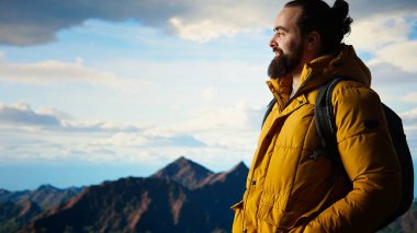Sıcak giysiler içindeki gezgin panoramik dağ sırasına bakıyor, macera duygusunu kucaklıyor ve en nefes kesici manzaraları keşfetmekle gelen kişisel gelişimi kucaklıyor. Kamera A.
