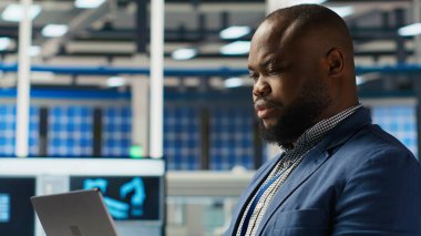 Neşeli fotovoltaik bitki uzmanı ofiste dayanıklılık ve performansta yenilikçi buluşlar üzerinde çalışıyor. Neşeli Afrikalı Amerikalı araştırmacı güneş panelleri için test materyalleri, kamera B