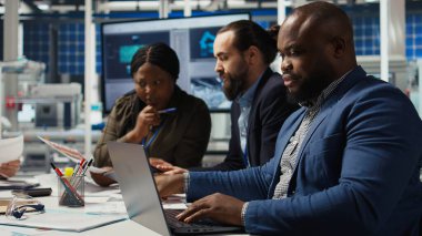 Fabrika yöneticisi laptopu kullanarak, üretimi genişleterek karlı bir iş modeli geliştiriyor. Adam endüstriyel fabrikada otomasyon teknolojisi entegre etmeye çalışıyor, not defterindeki ekipmanlara bakıyor, kamera A