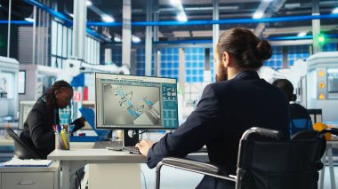 Fotovoltaik tekerlekli sandalyeli fabrika işçisi güneş paneli imalatının performansını izlemek için bilgisayarı kullanıyor. Bilgisayarda güneş santrali makinelerini denetleyen engelli kişi, kamera A