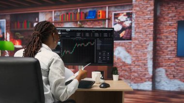 Bilgisayarı kullanan borsacı, iyi performans gösterebilecek hisse senedi alıyor ve değeri düşebilecek hisse senedi satıyor. Bilgisayar masasında hisse senedi portföy sayfalarına göz atan eski tüccar, kamera B