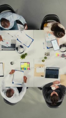 Yatırımcılar grubuyla birlikte performans raporlarını, sezgilerini ve planlarını tartışan bir konferans görüntüsü. Profesyonel ekip finansal verileri değerlendirir ve hedefler için tahminlerde bulunur. Kamera A.