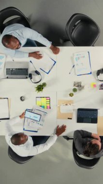 Vertical Video Top, çok uluslu şirket ofisindeki personelin görüntüsünü büyüt, şemaları ve iş haritalarını incele. İş arkadaşları şirket planlamasını geliştirmek için görüşlerini ve tahminlerini paylaşıyorlar. Kamera A.