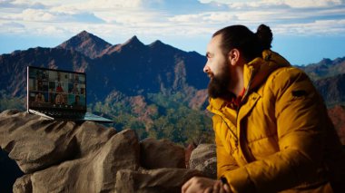 Macera Avcısı 'nın her yerde interneti var ve video görüşmelerini kullanıyor. Dağın tepesinde iş arkadaşlarıyla sohbet ediyor. Teknoloji saplantısı ve bağımlılığı olan bir yürüyüşçü. Kamera B.