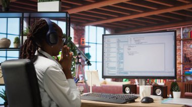 Bilgisayarda kulaklık takan heyecanlı programcı olumlu sonuçları gördükten sonra el çırpıyor. Memleketteki neşeli kadın uygulama, dinleme ve kamera A 'daki hataları düzelttikten sonra çok mutlu oldu.