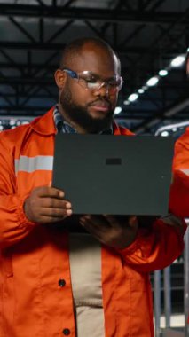 Metal makineler ve imalat araçlarıyla çevrili dikey video çeşitliliği işçileri çelik üretim işlerini yönetmek için cihazlar kullanıyorlar. Fabrika katında profesyonel mühendislik ve insan gücü. Kamera B