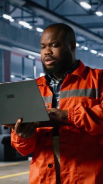 Vertical Video Industrial çalışanı, profesyonel denetimi desteklemek ve güvenli ve verimli çelik üretimi ve üretim akışını sağlamak için dizüstü bilgisayarı kullanarak bir depoda montaj çalışmalarını denetler.