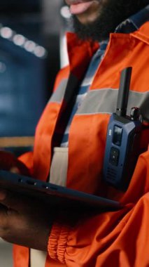 İnşaat işleri sırasında çelik makinelerinin yanında duran dikey video endüstrisi işçisi fabrika içinde üretim sorumluluğunu gösteriyor. Üretim sürecinde güç. Kamera B.