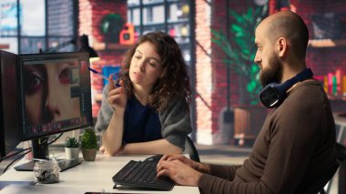 Erkek ve kadın yaratıcı ekip görüntü modelleri oluşturmak için yapay zekayı kullanıyor, dijital materyalleri geliştirmek ve kalite içeriği yaratmak için kurgu yazılımını çalıştırıyor. Fotoğraf rötuşlu yapay zeka asistanı. Kamera B.