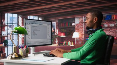 Teknolojiden anlayan siyah mühendis evde güvenli çevrimiçi program geliştiriyor. İkili verilerle çevrili olan serbest çalışan arayüz tasarımı, senaryo optimizasyonları ve ağ sistemleri üzerinde çalışıyor. Kamera B.