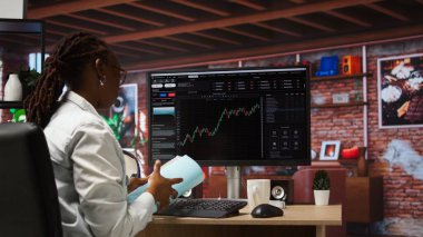 Bilgisayarı kullanan borsacı, iyi performans gösterebilecek hisse senedi alıyor ve değeri düşebilecek hisse senedi satıyor. Eski tüccar bilgisayar masasında hisse senedi portföyü sayfalarını karıştırıyor, kamera A