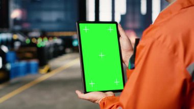 Dikey yeşil ekran, endüstriyel fabrikada metal aletlerin ve makinelerin yanında duran işçiler montaj vergilerini koordine etmek için ekipman kullanıyorlar. Yapısal üretim süreci. Kamera B.