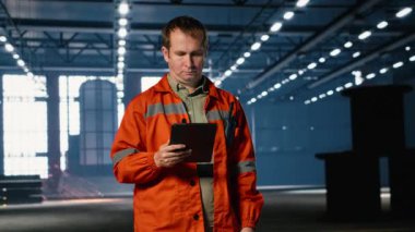 İşgücü teknisyenleri, kaynak alanlarından kıvılcımlar yükselirken tablet teçhizat kullanarak fabrika zemininde yürüyorlar. Bu da işletme ve endüstriyel fabrika gelişiminin profesyonel kontrolünü gösteriyor. Kamera B.