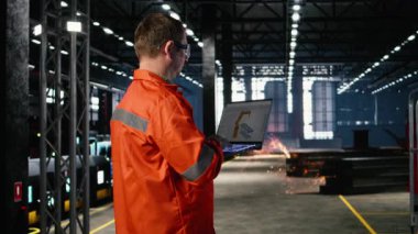 Mühendis, imalat ve inşaat işlerinde robot ekipmanlarını kontrol etmek için dizüstü bilgisayarda otomasyon yazılımı kullanıyor. Endüstriyel enerji ve endüstriyel fabrikada hassas mühendislik gelişimi. Kamera A.