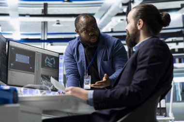 Profesyonel usta mühendisler kontrol panellerini inceliyor ve verileri analiz ediyor ve bir güneş enerjisi üretim tesisinde bilgi paylaşımı yapıyor. Teknik içgörü ve grup işbirliği.
