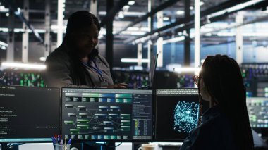 Veri merkezi yöneticisi verileri analiz etmek için düğüm ağacı yazılımı kullanan teknisyeni denetliyor. Sunucu odası takım lideri IT uzmanını vites performansını arttırmak için görsel programlama araçları kullanarak denetliyor, kamera B