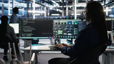 Veri Merkezi çalışanı, bildirilen sorunları gidermek için ses kulaklığı ve görsel programlama paneli kullanıyor. Sunucu çiftliği teknisyeni düğüm ağacı arayüzüne bakıyor, mikrofonla konuşuyor