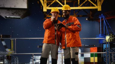 Radyo cihazlarıyla iletişim kuran endüstriyel işçiler kıyı platformunda teftiş ve izleme görevleri yerine getiriyorlar, sanayi içinde benzin ve petrol üretimini destekliyorlar..