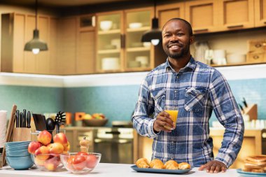 Elinde taze sıkılmış bir bardak portre portre portresi, organik ev yapımı kruvasanlar ve taze ekmek dilimleriyle yemek servisi. Mutfak tezgahında mutlu dengeli yaşam tarzı.
