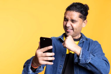 Cep telefonunu kullanarak tatmin olmuş, stüdyoda iyi haberler okuyan şık Hintli bir adamın portresi. İnternete bağlı sosyal medya uygulamaları ile kaydırılıyor.