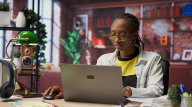 Teleworker masadaki verileri analiz ediyor ve evrak işlerini inceliyor, analitik raporları derliyor. Uzaktan çalışan belgeleri kontrol ediyor, şirket bilgilerini internete yüklemek için dizüstü bilgisayar kullanıyor, kamera B
