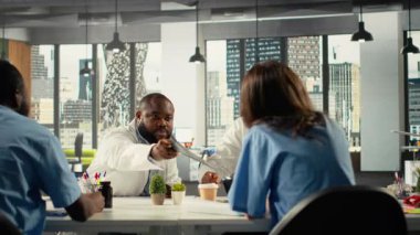 Çeşitli doktorlar klinik kayıtlarını inceleyerek hastanedeki sağlık hizmetlerini iyileştirmek için uzmanlık ve teşhis sonuçlarını paylaşmak üzere birlikte çalışıyorlar. Beyin fırtınası tedavi fikirleri. Kamera B.