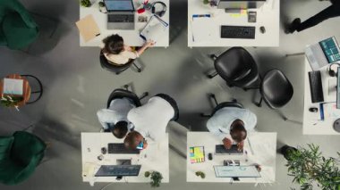 Ofisteki çeşitli personelin yukarıdan aşağı görüntüsü hava tahmini üzerinde çalışıyor. Etkili yönetim ve iş hedeflerini geliştirmek için profesyonel personel görsel verileri ve şemaları gözden geçirir. Kamera A.