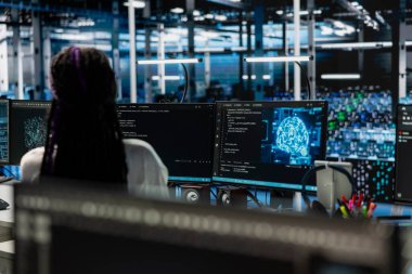 Sunucu merkezindeki kadın teknisyen ekipman donanımlarını incelemek için bilgisayar kullanıyor. Veri Merkezi çalışanı, sistem uptime 'ı korumak için sinirsel ağlar kullanarak performans verilerini analiz ediyor