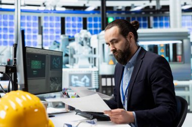 Bir güneş fabrikasındaki üretim hattının verilerini inceleyen usta mühendis, yeşil teknoloji ortamlarındaki liderlik ve alternatif enerji verimliliğinin değerini artırıyor. Güneş teknolojisi.