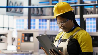 Akıllı güneş panelleri fabrika mühendisi üretim hatlarını denetlemek için tablet kullanıyor. Sektör 4.0 fotovoltaik fabrikasındaki kadın makinelerin en uygun verimlilikte çalışmasını sağlar.