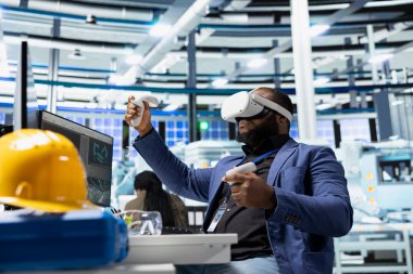 Fotovoltaik fabrikasındaki siyah mühendis arızalı sistemleri teşhis etmek için sanal gerçeklik ekipmanları kullanıyor. Kadın güneş panelleri denetleme için VR kulaklık kullanan fabrika işçisi, yüksek teknoloji.